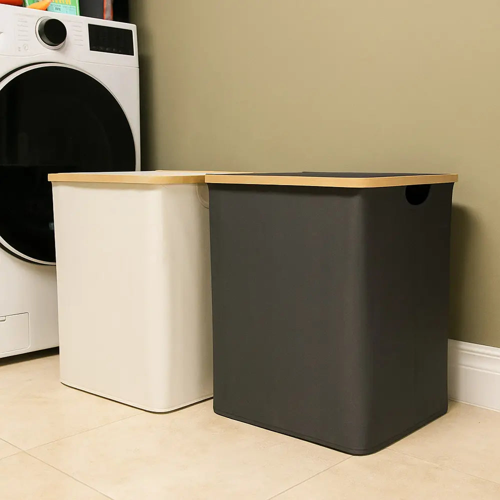 Black laundry basket with wooden top next to a washing machine in a laundry room.