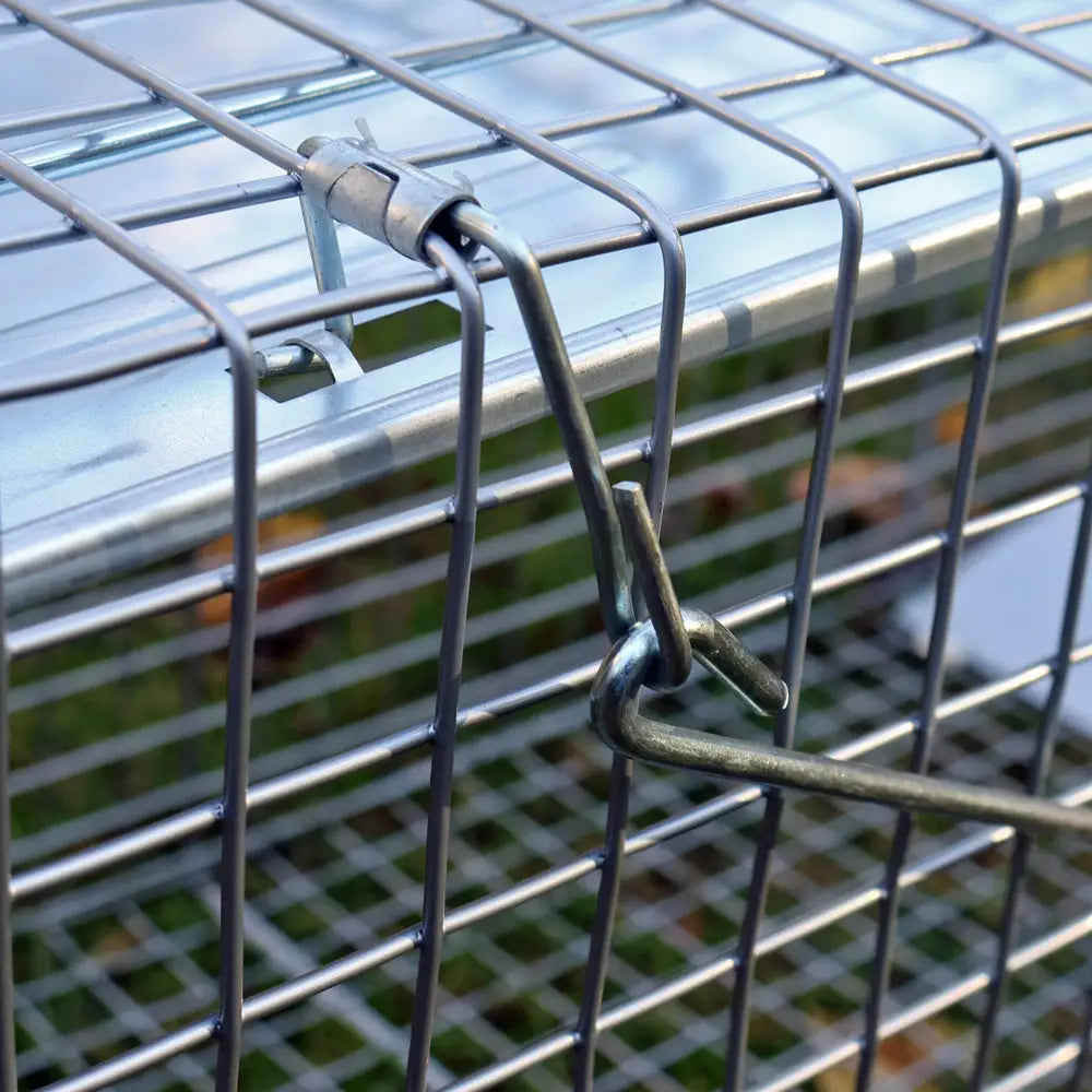 Metal wire cage with a latch on a blurred natural background