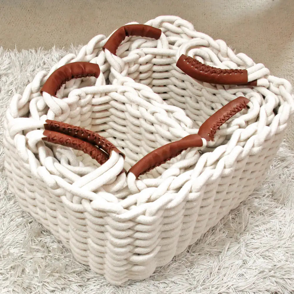 White woven basket with brown handles on a light background