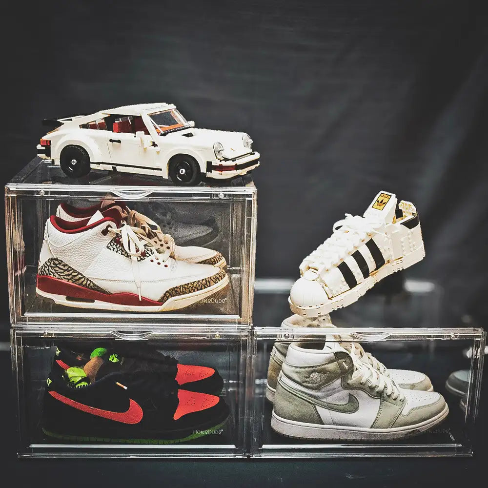 Collection of sneakers and a toy car displayed in clear cases against a dark background