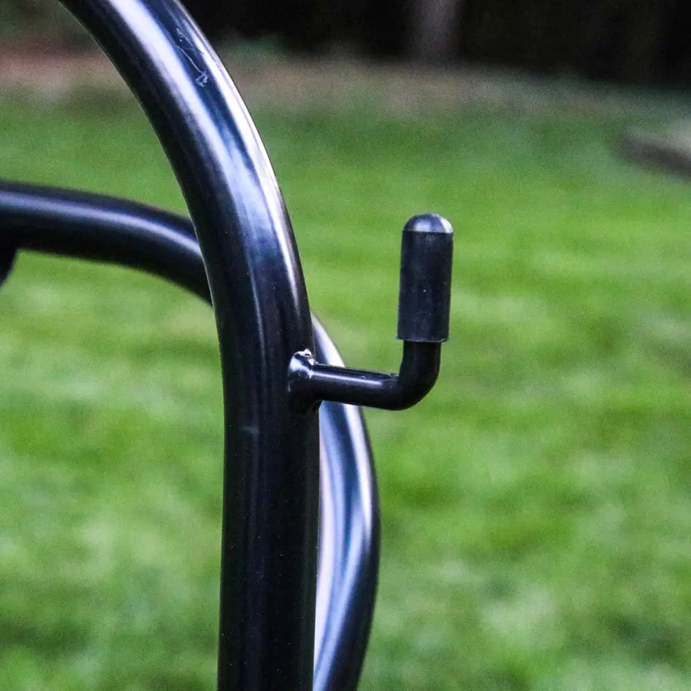 Close-up of a black metal hook of the saddle rack on a blurred green grass background