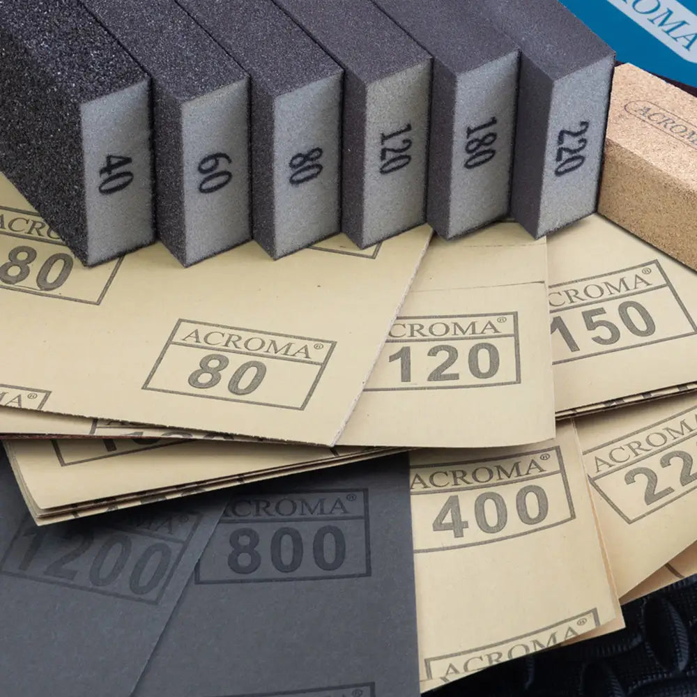 Set of sandpaper sheets with numbers indicating grit levels on a blue background.