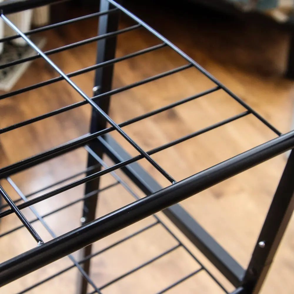 Close-up of a black metal wire rack on a wooden floor.