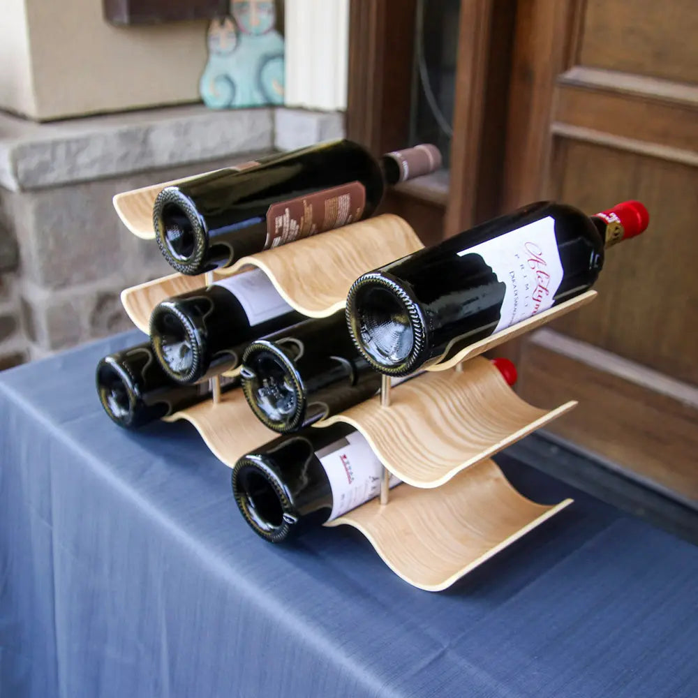 Wooden wine rack holding six bottles of red wine on a blue table.