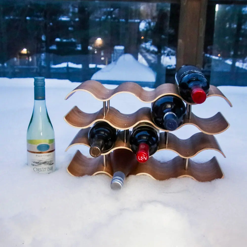Wooden wine rack with bottles on a snowy surface