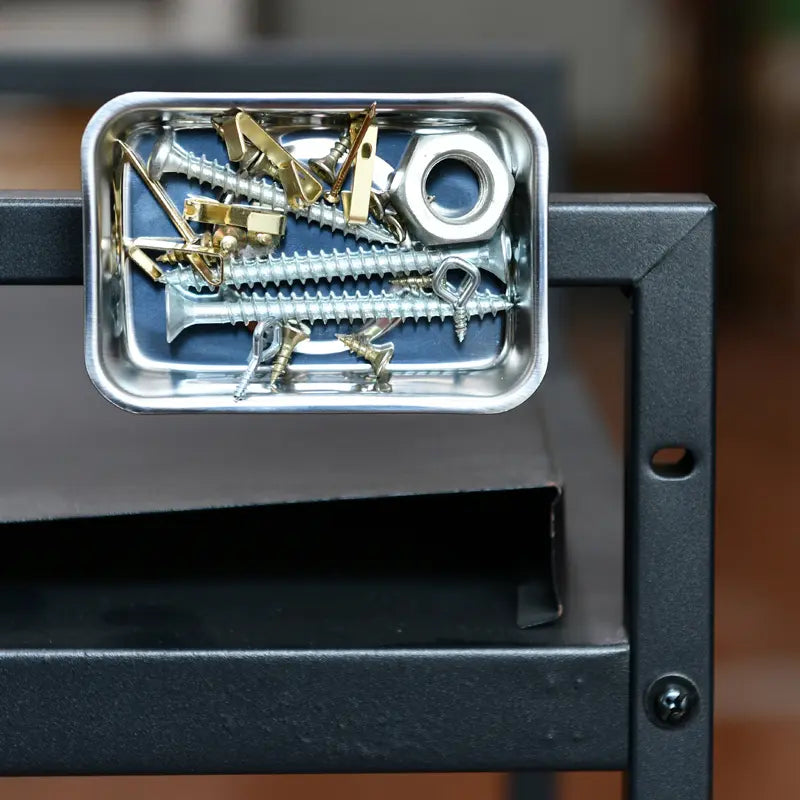 Metal tray with screws and washers on a black metal surface