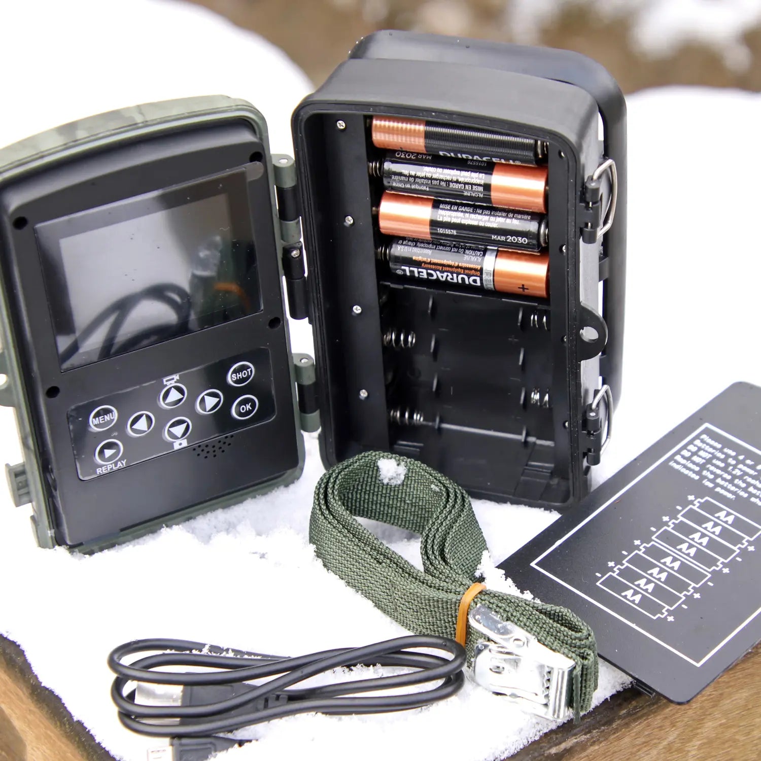 Back view of 4K trail camera showing LCD screen, control buttons, battery slots, strap, and USB cable.