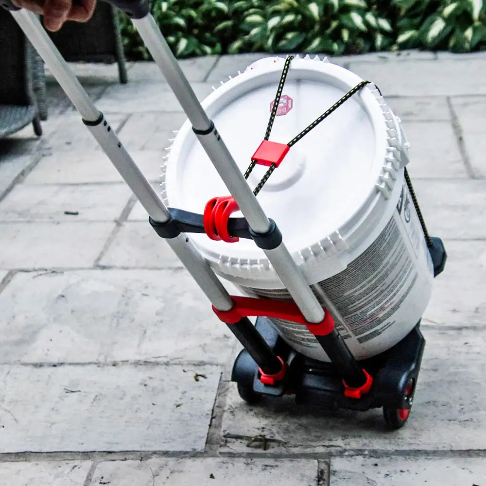Person using a dolly to transport a large white container with on a sidewalk.
