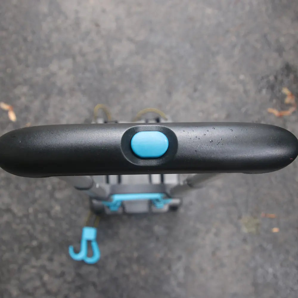 Close-up of a black handlebar with a blue button on a textured surface