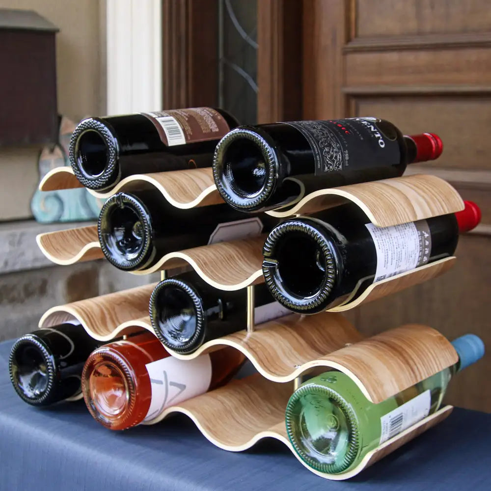 Wooden wine rack holding multiple bottles on a blue surface.