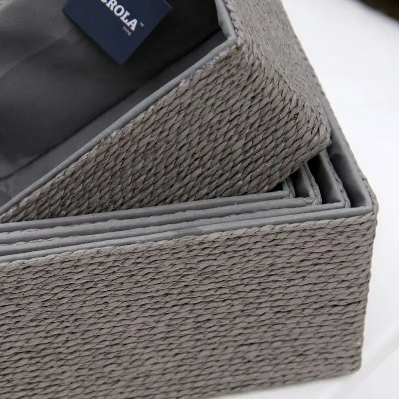 Gray woven storage baskets with a visible brand label on a white background